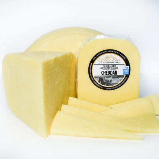 Block and slices of aged Cheddar cheese with label.