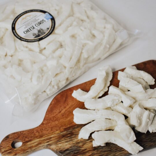 Packaged and sliced white rice cakes on a wooden board.