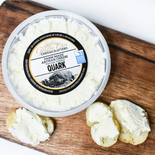 Container of creamy quark cheese with slices of bread spread with it.